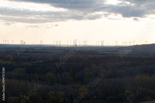 Wind turbines on horizon at sunset, renewable energy landscape with silhouettes against warm orange sky
