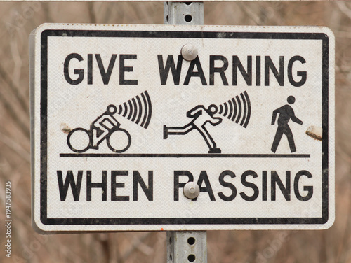 Foto Sign on a walking / hiking trail that says to give warning when passing