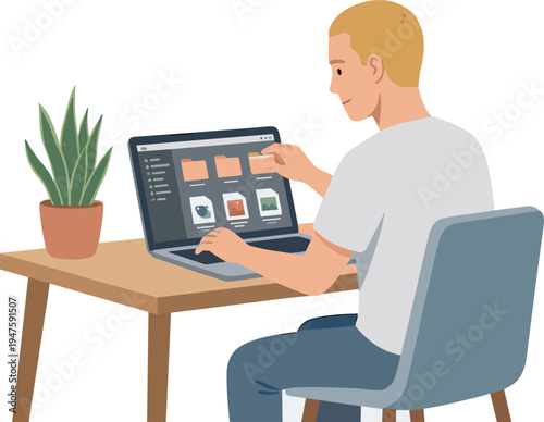 Man sitting at a desk working on a laptop with a plant nearby
