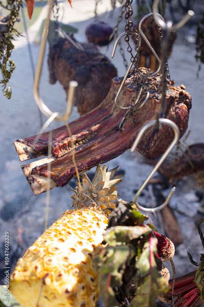 Obraz premium Hanging meat and vegetables over an open fire, the Australian bush cooking style. 