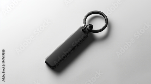Sleek black rectangular keychain on smooth white surface with shadow