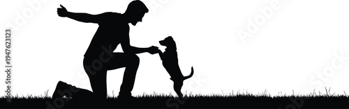 Man kneeling on grass giving dog a treat silhouette black white
