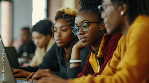 A group of young African American women using laptops in a classroom setting