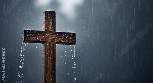 A wooden cross stands in heavy rain, with water dripping down its arms, against a dark and blurred background, evoking a somber atmosphere.