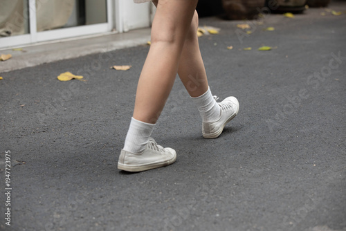 Female tourist in white sneakers walking, urban movement, candid tropical street life, street life, leg skin, low angle, at Wang Lang Market.