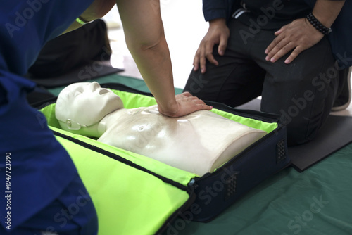 Healthcare worker performing chest compressions on a CPR training mannequin during an emergency first aid and life-saving skills workshop.