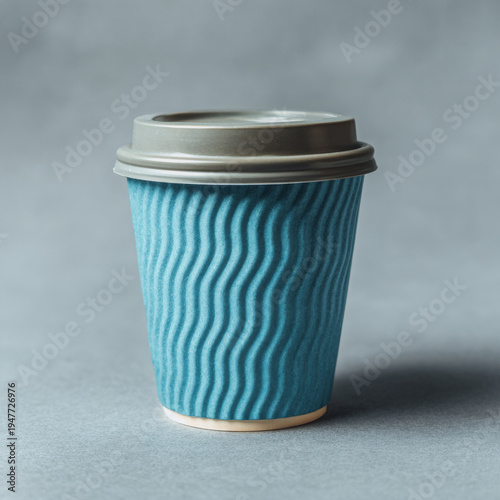 Blue paper coffee cup with wavy texture and gray plastic lid on gray background, simple and modern design for hot beverage