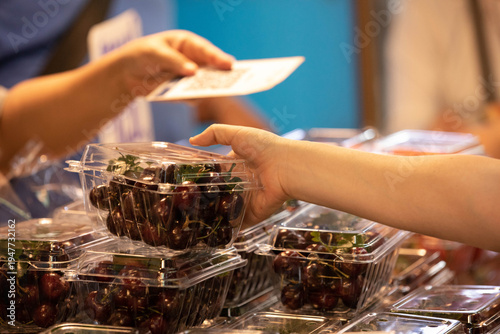 Woman choosing cherries in plastic box, woman shopping fruits in market, local vendor street commerce, close up, at Wang Lang Market.