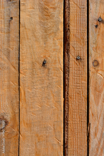 Close up view of vertical brown wooden planks with rough texture visible wood grain and metallic screws on a rustic surface