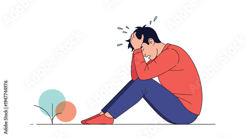 Depressed young man in a red shirt sitting on the ground with his head in his hands expressing sadness or grief.