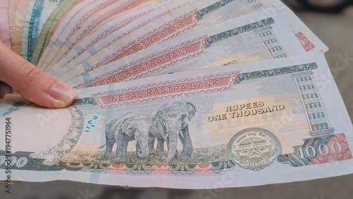 Hand holding Nepali Rupee banknotes