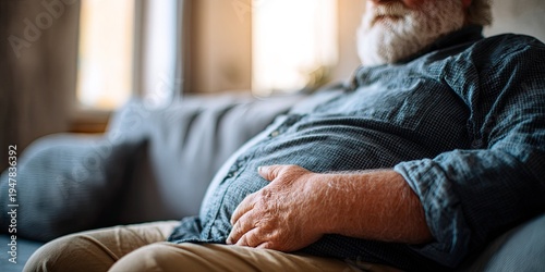Elderly Man with Large Belly Sitting on Sofa.