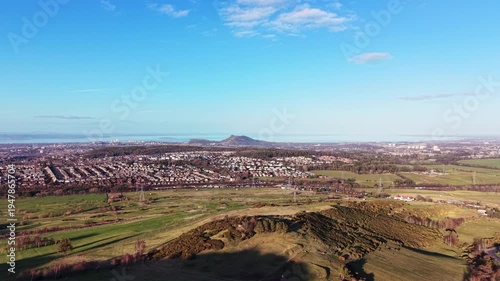 Aerial panorama of Edinburgh from Hillend: Cinematic drone flight over Midlothian farmland towards the city skyline and Firth of Forth