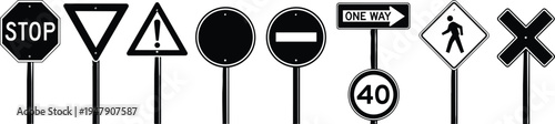 Set of black and white road traffic signs including stop, speed limit, pedestrian crossing, and warning signals on poles.
