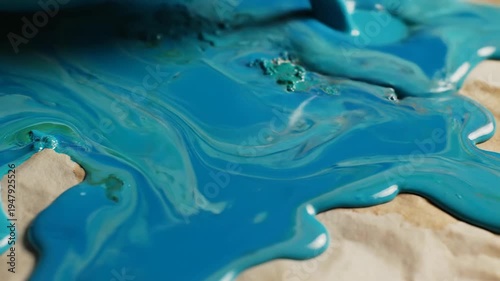 Vibrant turquoise paint washes over textured parchment paper creating a flowing abstract art design