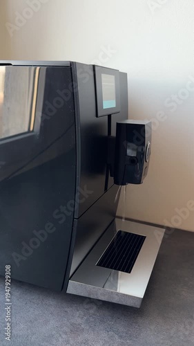 Automatic coffee machine rinse. Water leaking from the coffee machine. An expensive coffee machine with an automatic self-cleaning system. A black coffee machine in the interior.