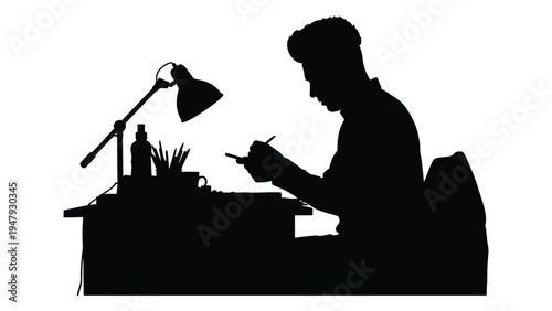 Man sitting at desk writing with a lamp on