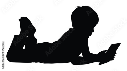 A child lies on their stomach and uses a tablet