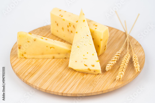 Slices of semi-hard cheese with nuts on a wooden board