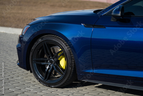 Side view of the front wheel and fender of a dark blue luxury sedan