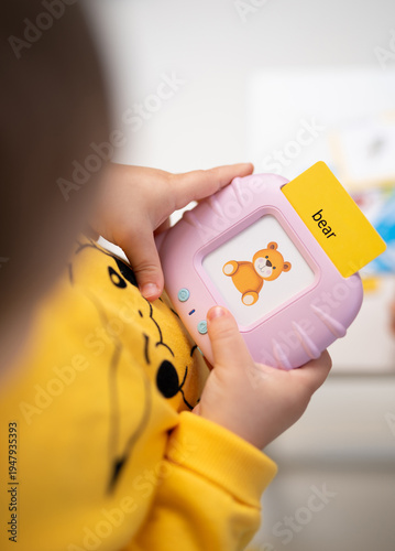 Toddler playing with a pink electronic flashcard learning toy