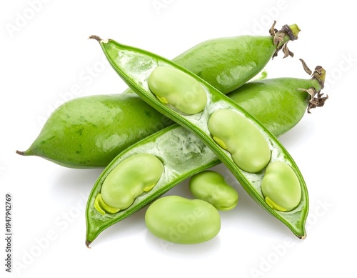 Fresh fava beans, some split open, display pale green beans.  They are scattered on a white surface