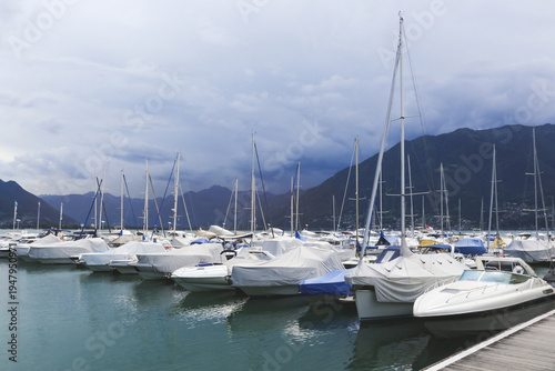 Scenic marina with moored yachts and sailboats against a mountain backdrop in Switzerland