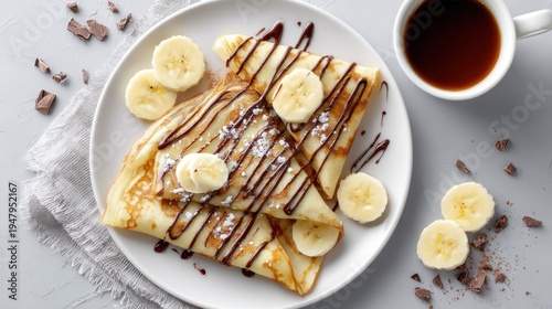 Delicious crepes with chocolate drizzle and fresh banana slices served with coffee