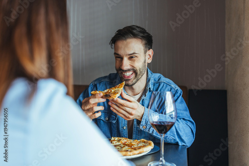 Smiling Man Enjoying Pizza and Red Wine on a Casual Restaurant Date With Partner