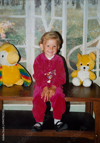 Authentic 1990s family snapshot of smiling little girl with plush toys
