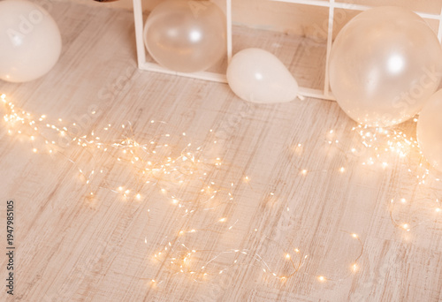 Fairy lights and white balloons on wooden floor