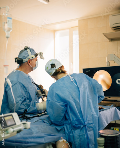 Photos Medical team consisting of two surgeons operating on a patient using specialized