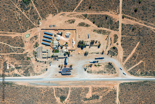 Aerial top-down view of a remote roadhouse with solar panels and trucks by a highway