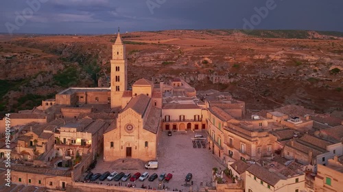 Aerial reveal of Matera at twilight as street lights turn on