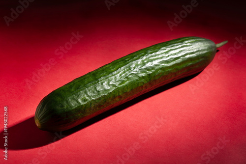 one cucumber on red background