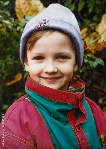 Smiling little girl in colorful jacket and knit hat, nostalgic 1990s childhood portrait