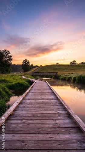 A serene wooden boardwalk over a river at sunset in a rural landscape