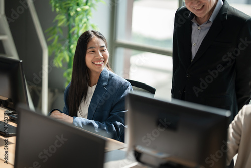 Happy young Asia business woman sitting on her workplace and working with computer in the office