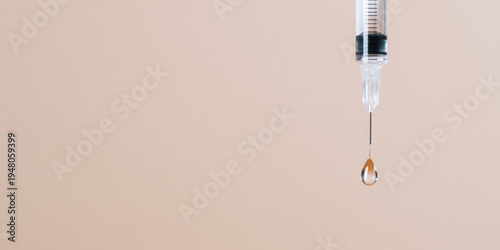 Syringe with clear liquid drop hanging from needle tip on soft beige background, minimal style close up showing precise medical equipment detail