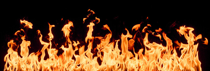Bright orange and yellow flames dance intensely against a dark, black background, creating a dramatic display of heat, power, and energy.