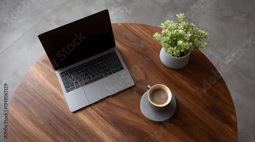Overhead view of a laptop coffee cup and plant on a wooden table in a modern setting