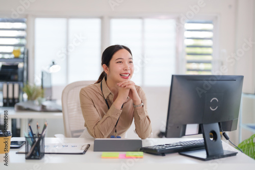 Asian adult woman professional employee happy working office desk computer display monitor engagement business corporate environment bright modern workplace success future vision