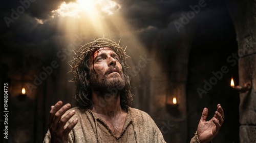 Jesus Christ wearing crown of thorn looking up to heaven with arms raised in dark stone room illuminated by divine light. Biblical religious scene representing sacrifice and faith.