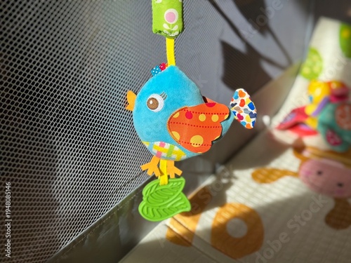 Wallpaper Mural A plush baby rattle toy shaped like a little bird hanging in a baby playpen, illuminated by bright sunlight. Torontodigital.ca
