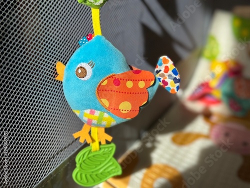 Wallpaper Mural A plush baby rattle toy shaped like a little bird hanging in a baby playpen, illuminated by bright sunlight. Torontodigital.ca