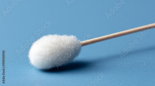 A cotton swab with a wooden stick on blue background