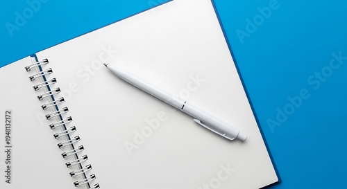 A white pen rests on an open blank notebook page against a blue background.