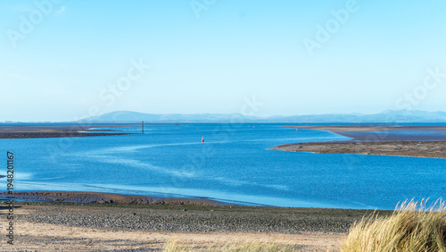 A seascape at low tide with a blue sky, Morecambe Bay. The seashore and the sea against a backdrop of hills on the horizon