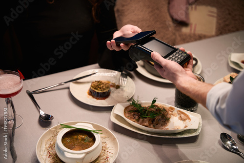 Two people making contactless payment in restaurant at evening