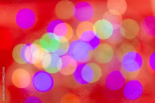 Abstract multicolored bokeh light circles softly blurred over a bright red background, creating a vibrant festive atmosphere.
